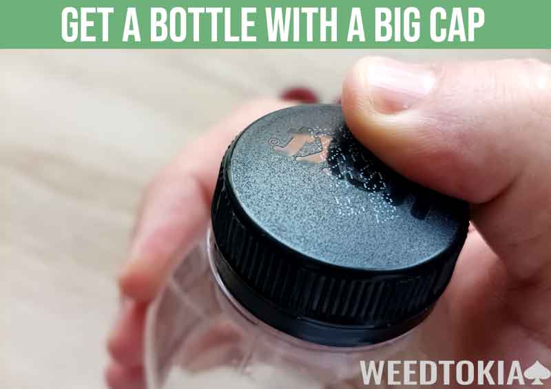 Bottle with a big cap measured next to thumb