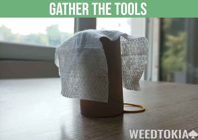 Gather dryer sheets, empty toilet paper cardboard roll, and rubber band